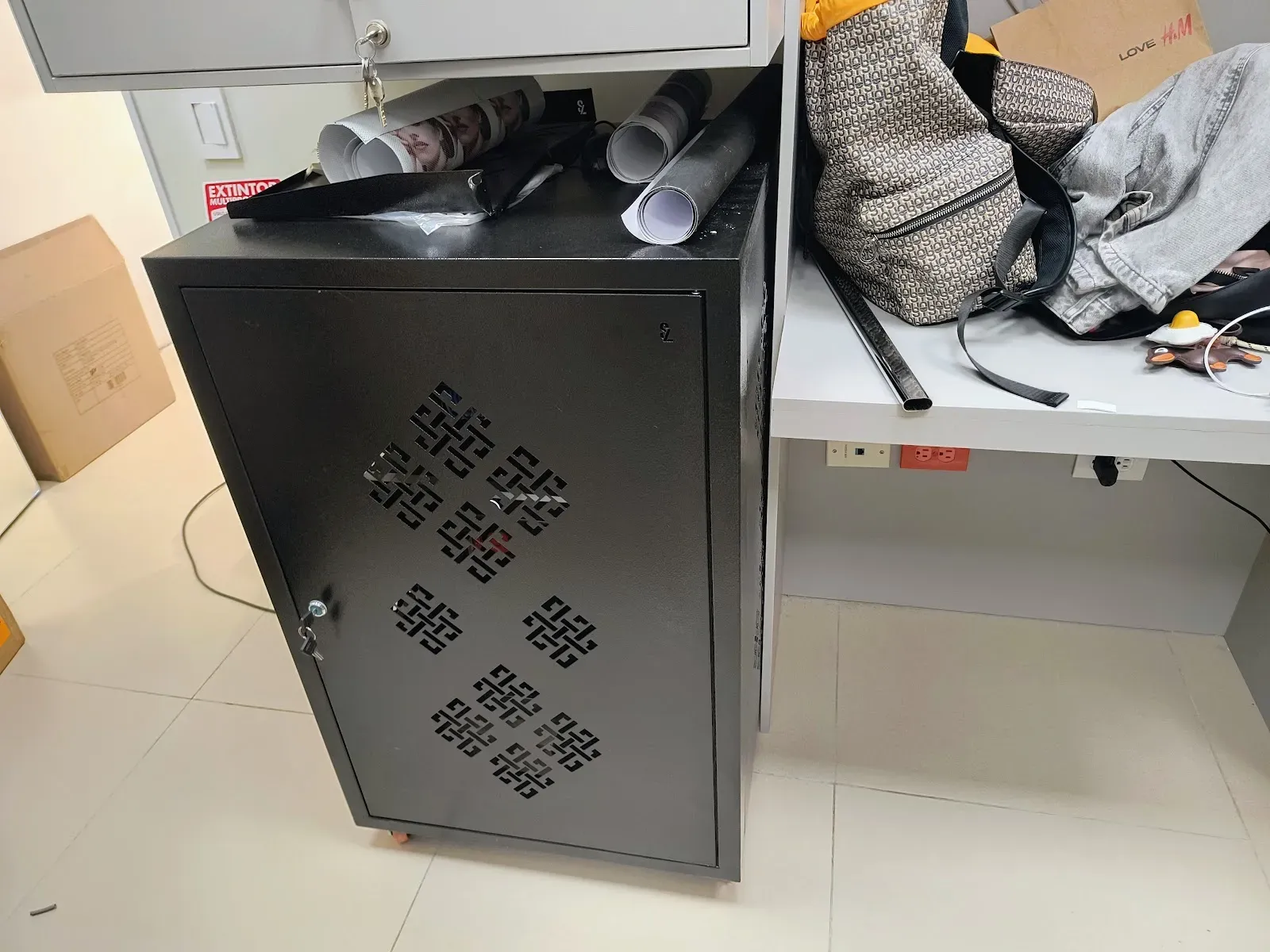 Gabinete de comunicaciones negro con puerta perforada y cerradura, ya instalado y cerrado en la trastienda del local