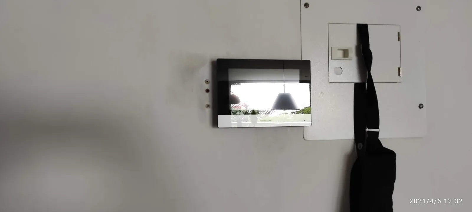 Monitor de video portero instalado en la pared del apartamento, encendido y mostrando en vivo la imagen del acceso al edificio